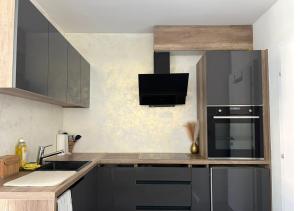 a kitchen with black cabinets and a sink and a microwave at Studio lumineux in La Chaux-de-Fonds +2 photos