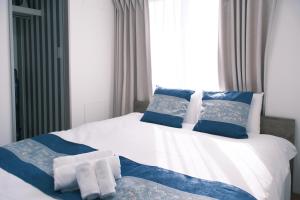 a bedroom with a white bed with blue pillows at The Peak Tsutenkaku Apartment Hotel in Osaka +37 photos