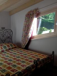 a bedroom with a bed with a quilt and a window at Villa Susina in Toscolano Maderno