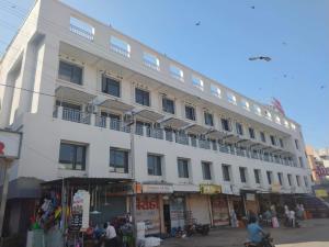 a white building with people standing outside of it at Hotel Mahavir in Ankleshwar
