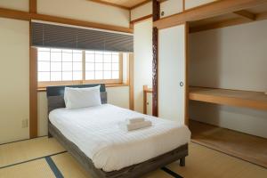 a bedroom with a white bed with a window at Asahikawa Kawabata House in Asahikawa