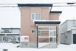a building with a glass door in the snow at Asahikawa Kawabata House in Asahikawa