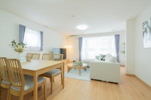 a dining room and living room with a table and a couch at Asahikawa Kawabata House in Asahikawa