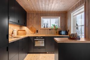 a kitchen with black cabinets and a window at Flott utsikt Peis Elbillader in Aurdal