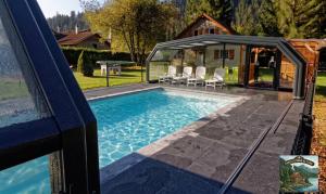 a pool with a gazebo next to a house at Chalet Lodge - O'Bord de l'Eau in Gérardmer
