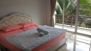 a bed in a bedroom with a large window at Aple Homestay in Amphawa
