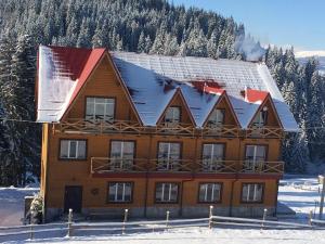 a large wooden house with snow on the roof at Dream House in Yablunytsya