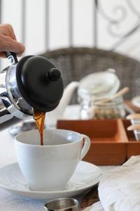 a person pouring coffee into a cup on a table at Maison d'hôtes Urbegia in Ascain