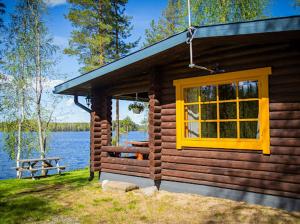 a log cabin with a yellow window and a bench at Juhantupa in Keuruu