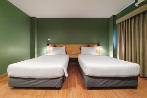 two beds in a room with green walls at MyBed Ratchada in Bangkok