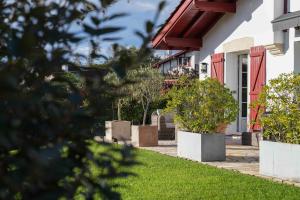 a house with potted plants in front of a yard at Maison d'hôtes Urbegia in Ascain