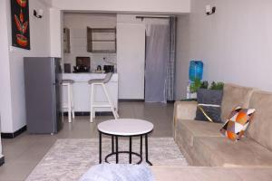 a living room with a couch and a table and a kitchen at Gessy Homes in Eldoret