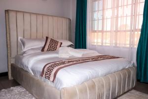 a bed in a bedroom with a large window at Gessy Homes in Eldoret +2 photos
