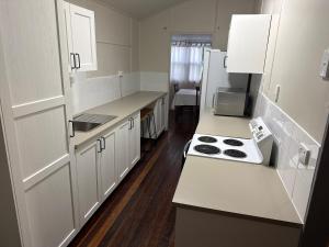 a kitchen with white cabinets and a stove top oven at The Beach Shack Yeppoon in Yeppoon