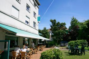 un groupe de personnes assis à des tables à l'extérieur d'un bâtiment dans l'établissement Parkhotel, à La Panne