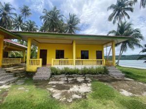 a yellow house with palm trees in the background at Harus Damai Inn in Lagudri +29 photos