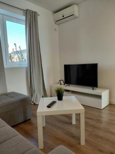 a living room with a tv and a table at Apartments and room Maressa Centar in Vodice
