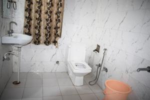 a white bathroom with a toilet and a sink at Amar Bagh Ranthambore in Khilchipur