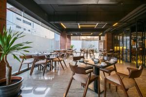 ein Restaurant mit Tischen und Stühlen in einem Raum in der Unterkunft Luminor Hotel Pecenongan Jakarta By WH in Jakarta