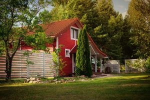 a red house with a red roof and a yard at Dom Yarla in Janowiec
