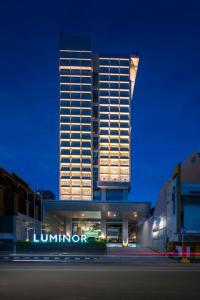 un edificio alto con un letrero iluminado delante de él en Luminor Hotel Pecenongan Jakarta By WH en Yakarta