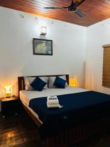 a bedroom with a large bed with blue pillows at Nature Land in Alleppey