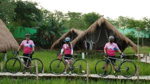 three people in pink shirts standing next to their bikes at Mudita Glamping and Villas Tarlac in Mababanaba