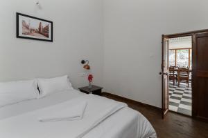a bedroom with a white bed and a sliding glass door at Hideaway Art Residency in Ooty