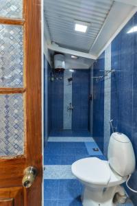 a bathroom with a toilet and a shower with blue tiles at Hideaway Art Residency in Ooty +15 photos