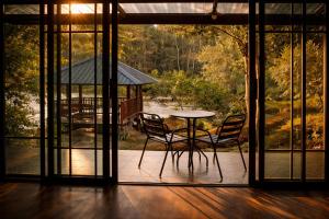 a table and chairs in a room with windows at Nalintara resort นลินธารารีสอร์ท in Ban Pha Saeng Lang
