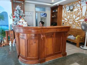 a woman standing behind a wooden counter in a room at HP Truong Hotel Phu Quoc in Phú Quốc