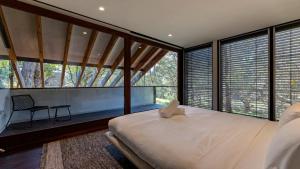 a bedroom with a large bed and large windows at Architectual Design, Plunge Pool, Lagoon Frontage in Pearl Beach