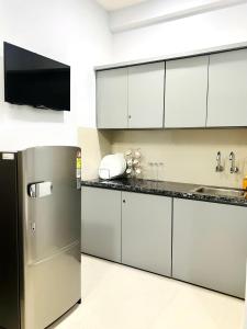 a kitchen with white cabinets and a stainless steel refrigerator at Nexaura Stays in Indore