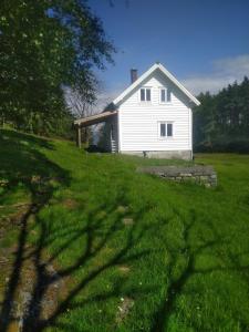 a white house in the middle of a grass field at Nernesholmen in Nes