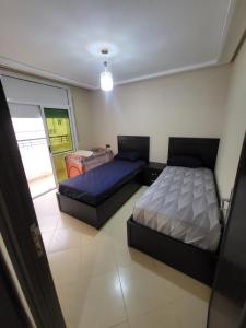 a bedroom with two beds and a door to a garage at appartement NADOR wifi gratuit clima mobile in Selouane