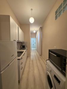 a kitchen with white appliances and a long hallway at Limore Hostel in Tirana
