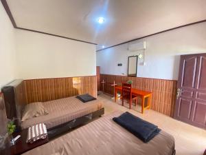 a bedroom with two beds and a table and a door at Harus Damai Inn in Lagudri