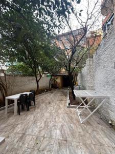 a patio with tables and chairs next to a wall at Limore Hostel in Tirana
