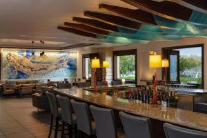 a restaurant with a bar with chairs and wine bottles at The Westin Sacramento Hotel & Marina in Sacramento