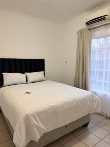 a bedroom with a large white bed with a window at Vellora Haus in Burgersfort