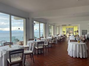 a restaurant with white tables and chairs and windows at Bay Palace Mazzarò in Taormina