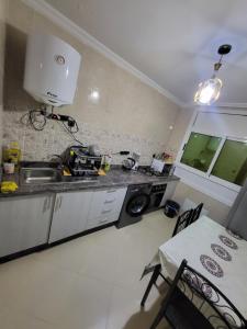 a kitchen with a sink and a stove and a table at appartement NADOR wifi gratuit clima mobile in Selouane