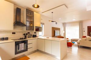 a kitchen with white cabinets and a living room at Elle Apartments in Lusaka
