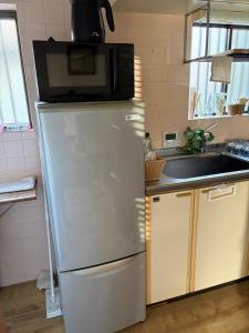 a microwave on top of a refrigerator in a kitchen at AppleHouse高瀬駅 in Mitoyo