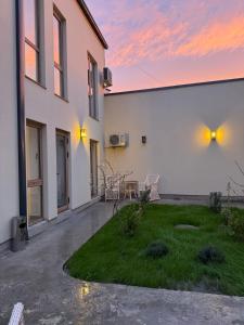 a white building with a patio and a grass yard at Sa'ada Boutique Studios in Bukhara