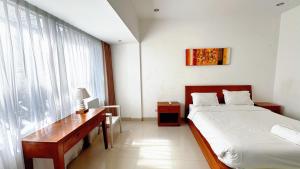 a bedroom with a bed and a desk and a window at Cozy Guest House Canggu in Kerobokan +20 photos