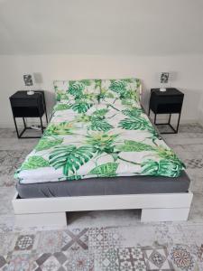 a bed with a green and white bedspread and two tables at Monstera Apartment in Groß-Umstadt