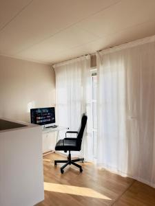 a desk with a chair in a room with a window at Large apartment with parking in Sandefjord