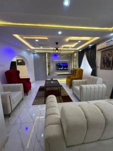 a living room with white couches and a tv at Q2Shortlet Apartment in Isheri-Olofin