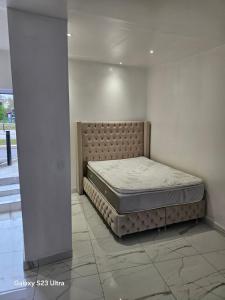 a bed sitting in a room next to a wall at Emmanuel INN XI in Pierrefitte-sur-Seine